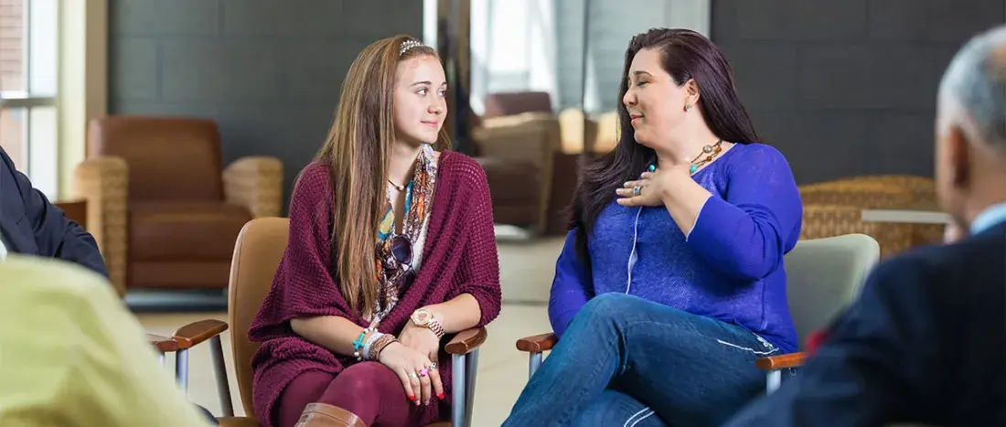 Woman and teenager talking during diverse support group meeting